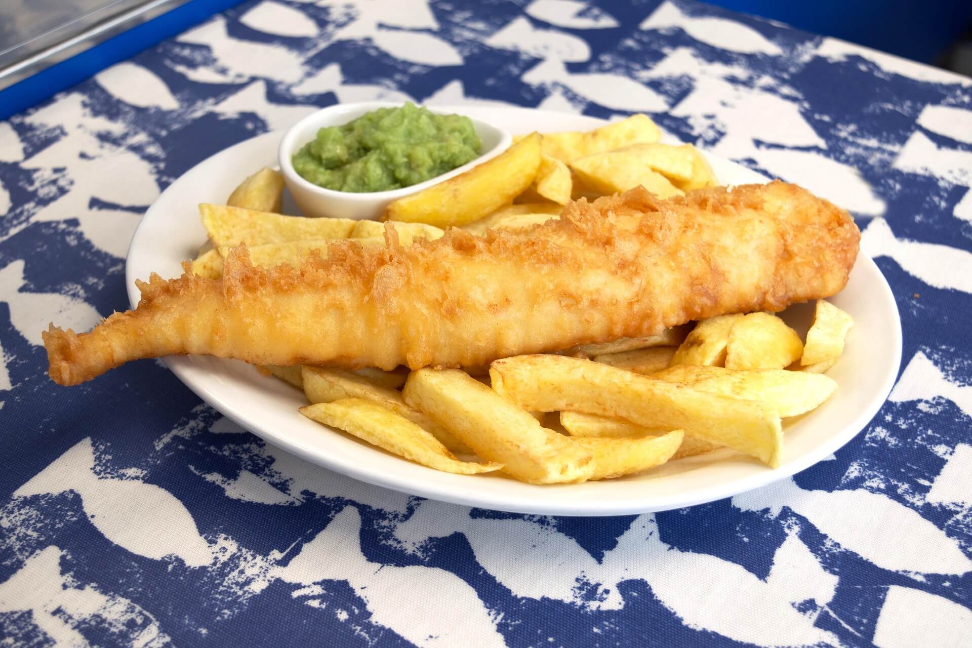 A portion of fish and chips with peas